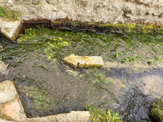 stone arrow pointing westwards into a stream bed